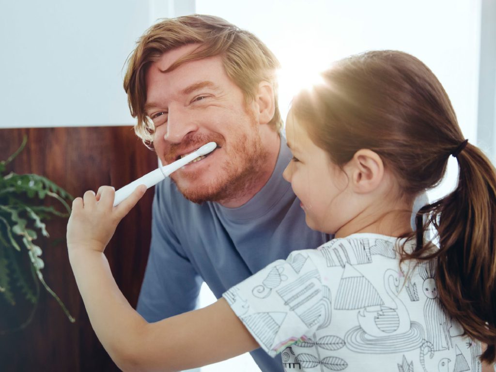 Content Zahngesundheit Mädchen putzt dem Vater die Zähne