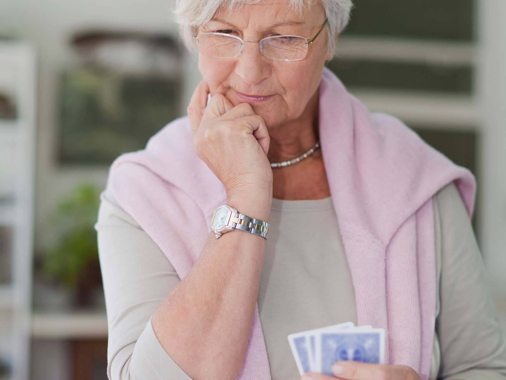 Ältere Frau spielt Soltaire und überlegt. Spielen