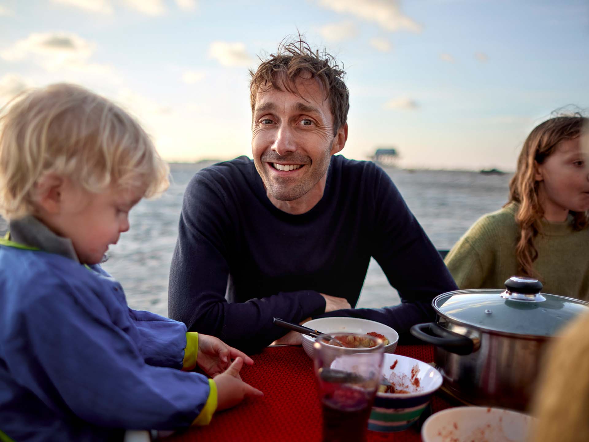 Mann frühstückt mit Kindern am Strand. Thema Herzinfarkt