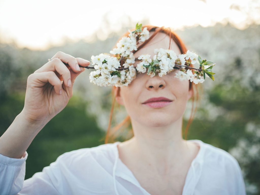 Junge Frau im Frühling mit Kirschblütenzweig. Thema: wetterbedingte Migräne